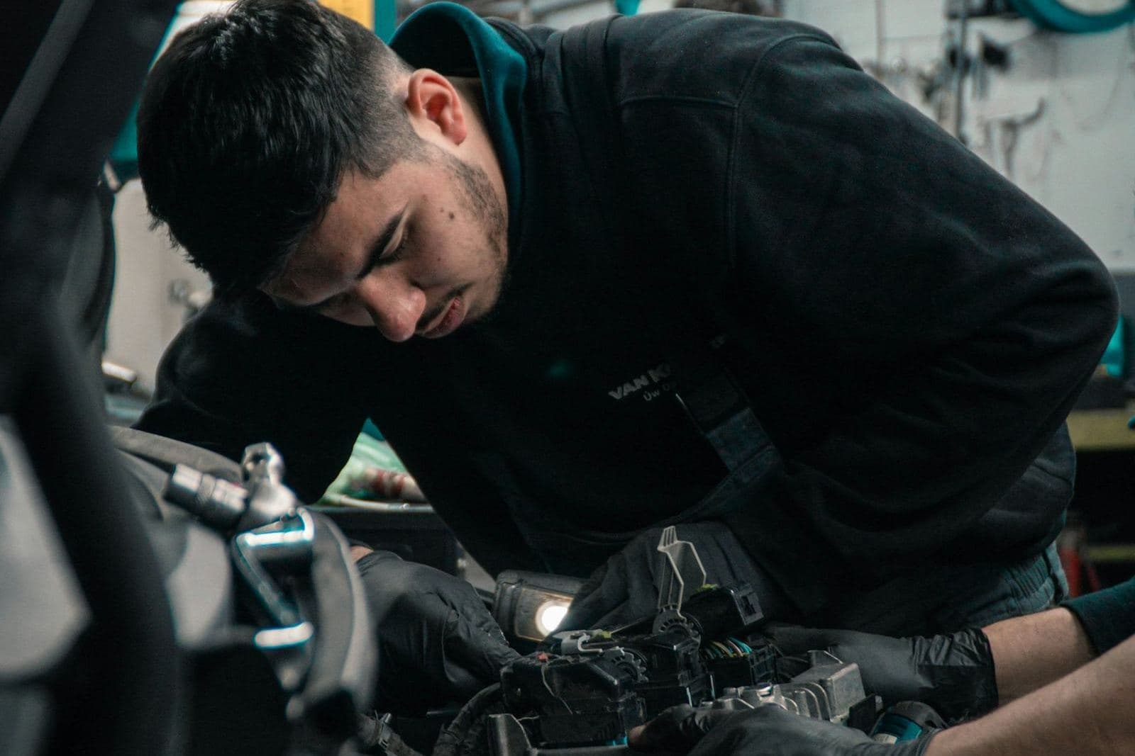 Technicien penché sur le moteur d’un véhicule dans un atelier