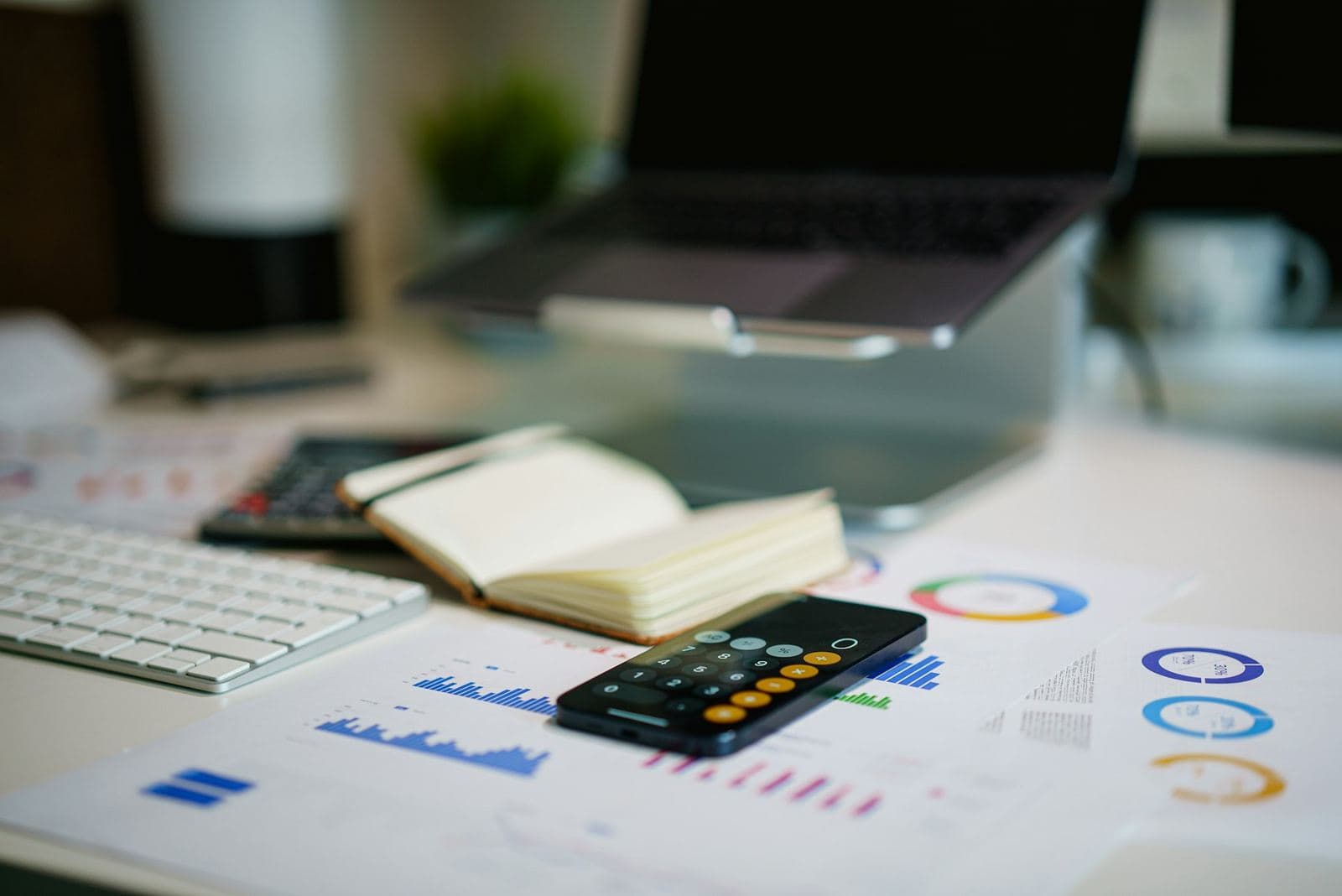 Bureau avec des tableaux de chiffres, une calculatrice et un ordinateur portable
