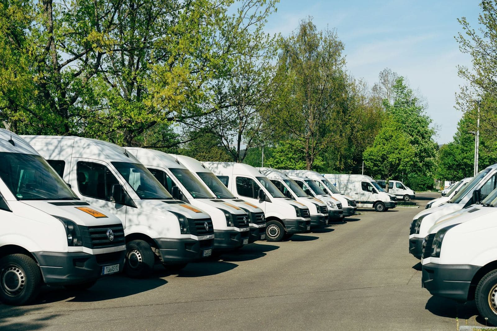 Une rangée de fourgons utilitaires blancs stationnés sur le parc d’une entreprise
