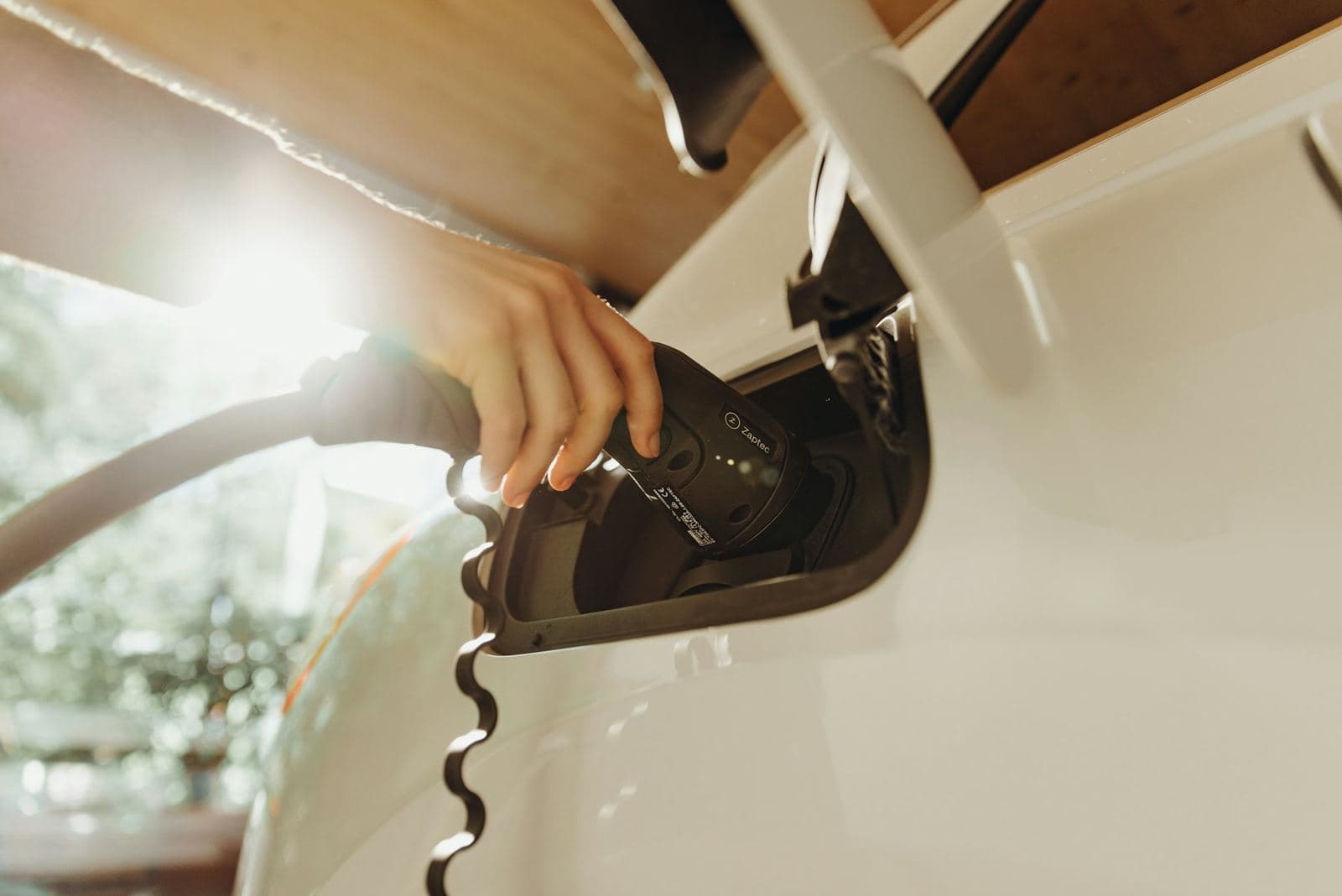 Main branchant un câble de recharge sur un véhicule utilitaire électrique
